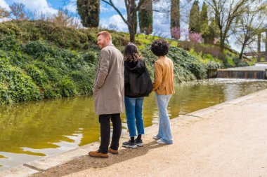 Üç arkadaş parkta dinlenen bir günün tadını çıkarıyorlar. Gölün sakin sularını inceliyorlar.