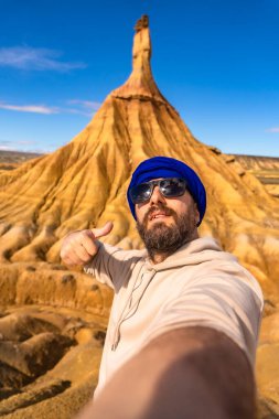 Bardenas 'ta selfie çeken ve işaret eden turistler kumtaşı oluşumunun önünde çöl, Navarre, İspanya