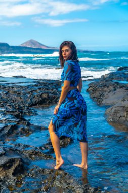 Güzel sahil kasabası Arucas 'ta çıplak ayakla volkanik kayalarda yürüyen genç bir kadın, Büyük Kanarya, tatilinin tadını çıkarıyor.