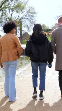 Genç arkadaşlar birlikte güneş parkında yürüyor, neşeli yaz haftasonu boyunca kahkahalarınızı paylaşıyor ve kaygısız anların tadını çıkarıyorlar, mutluluk ve yakın arkadaşlık yayıyorlar.
