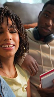 Genç öğrenciler eğlenceli bir şekilde selfie çekiyorlar, rahat bir yaşam alanında neşeli anlar paylaşıyorlar, gerçek bir bağ ve mutluluk sergiliyorlar.