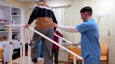 Huzurevinde bir fizyoterapistin yardımıyla rehabilitasyon egzersizleri yapıyor.