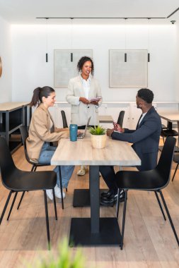 Çok ırklı iş adamları modern bir ofiste bir proje üzerinde çalışıyor, stratejileri tartışıyor ve fikirleri paylaşıyorlar.