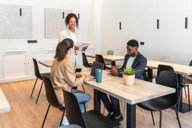 Projede işbirliği yapan çok ırklı iş adamları, parlak, modern bir ofis kafeteryasında fikirleri paylaşıyorlar, takım çalışmasını ve yenilikleri teşvik ediyorlar.