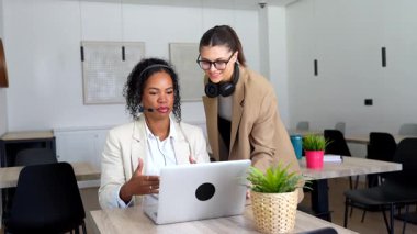 İki kadın müşteri hizmetleri temsilcisi bir dizüstü bilgisayarda iş ile ilgili konuları tartışıyor.