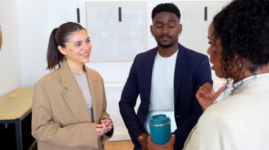 Profesyonel ekip üyeleri iş molasında gündelik sohbete girişiyor, fikirleri dinamik vücut dili ve işbirlikçi ruhla paylaşıyorlar.