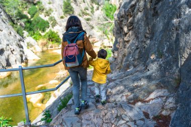Anne ve oğlu, Gandesa, Tarragona 'da yer alan ve doğayla çevrili güneşli bir günün tadını çıkaran bir tapınak olan la fontcalda' da, Canaletes nehri boyunca yürüyorlar.