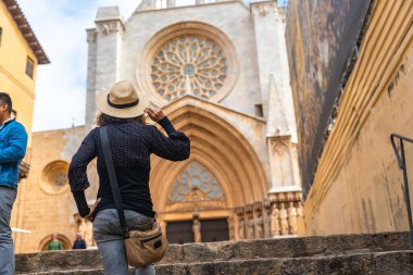 Tarragona, Katalonya ve İspanya 'da bir Roma Katolik kilisesi olan Tarragona' nın metropolitan katedrali Bazilikasını ziyaret ederken hasır şapkasını tutan bir turist.