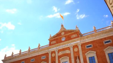 Tarragona 'daki belediye binası cephesi canlı mavi gökyüzüne karşı katalan bayrağı sallayarak mimari mirası ve kültürel önemi vurguluyor.