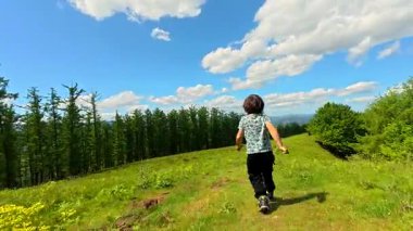 Genç çocuk Bask kırsalında yürüyüş yapıyor, Aldura dağının yakınındaki çimenli bir patika boyunca koşuyor.