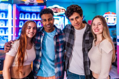 Dört genç çok ırklı arkadaş gülümsüyor ve atari salonunda eğleniyorlar. Hafta sonunun tadını çıkarıyorlar.