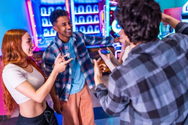 Çok ırklı arkadaşlar hafta sonunun tadını çıkarıyorlar, atari oyunları oynuyorlar ve renkli bir eğlence merkezinde eğleniyorlar.