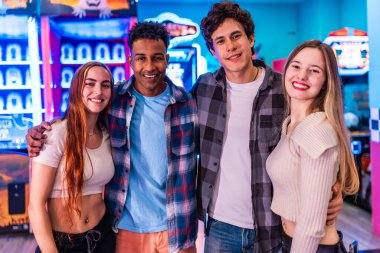 Dört genç çok ırklı arkadaş bir atari salonunda gülümsüyor ve eğleniyorlar, çeşitli oyun ve eğlence seçeneklerinin tadını çıkarıyorlar.