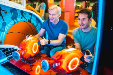 Renkli ışıklarla aydınlatılmış oyun makinesinde arkadaşça bir yarışmanın keyfini çıkaran iki genç adam, bir eğlence mekanında bir hafta sonu boyunca...