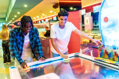 İki genç adam canlı bir bowling salonunda hokey oynuyorlar.