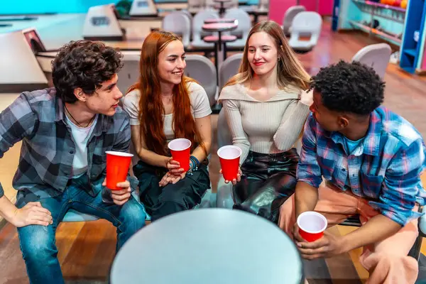 Dört genç arkadaş bovling salonunda takılıyorlar, ellerinde kırmızı bardaklar ve canlı sohbetler var.