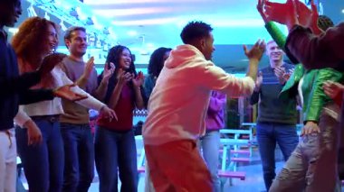 Genç, farklı arkadaşlar paten diskosunda neşeli anlar paylaşıyorlar, enerjik bir şekilde dans ediyorlar, el çırpıyorlar, gece hayatını coşkulu, kaygısız bir ruh ve bulaşıcı bir ritimle kutluyorlar.