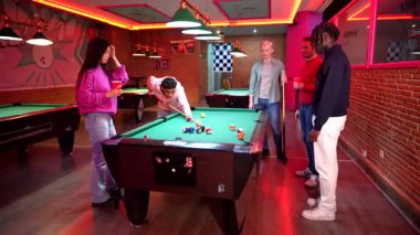 Genç yetişkinler canlı, neon ışıklı bir barda bilardo oynuyorlar. Arkadaşları arasında enerjik bir gece hayatı ve sosyal etkileşim sergiliyorlar.