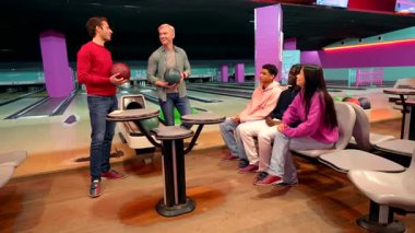 Bowling hocası bowling salonundaki çeşitli öğrencilere bowling tekniğini anlatıyor.