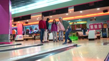 Arkadaşlar bovling oynamaktan hoşlanıyor, gülüyor ve grevleri kutluyor renkli bowling salonunda ortak heyecan ve takım ruhuyla yarışıyorlar.