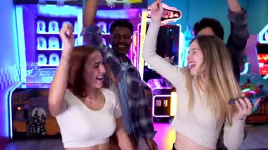 Renkli neon ışıkları altında dans eden, gülen ve eğlenen farklı arkadaşlar.