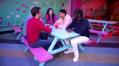 Arkadaşlar bovling salonundaki kutlama anlarını paylaşıyor, eğlenceli sosyal buluşmalar sırasında çeşitli gruplar arasında eğlenceli aktiviteler eşliğinde renkli kırmızı bardaklar kaldırıyorlar.