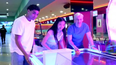 Mutlu arkadaşlar hava hokeyi oynamaktan zevk alıyorlar, coşku ve dostluk gösteriyorlar.