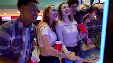 Mutlu arkadaşlar oyun salonunda eğleniyorlar, oyun oynuyorlar ve içki içiyorlar.