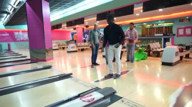 Bir grup arkadaş birlikte bovling oynarken, genç bir adam topu kulvara atmaya hazırlanıyor.