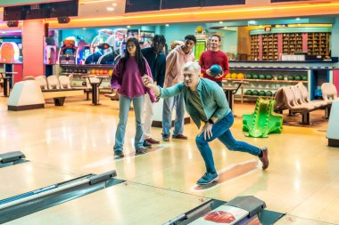 Çeşitli genç yetişkinler birlikte bovling oynayıp hafta sonları eğleniyorlar.