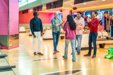 Eğlence merkezinde eğlenen çok ırklı arkadaşlar bir bowling maçından sonra birbirlerini tebrik ediyorlar.