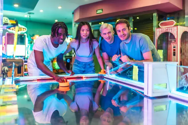 Çok ırklı dört genç arkadaş renkli ışıklarla dolu eğlenceli bir oyun salonunda eğleniyor ve eğleniyorlar.