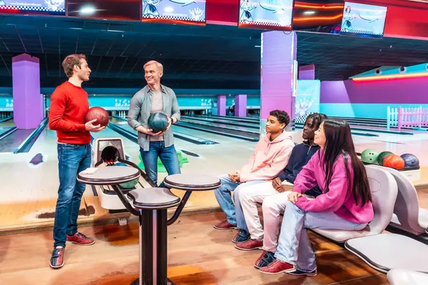 Bir grup çok ırklı arkadaş eğlence merkezinde bowling oynuyorlar.