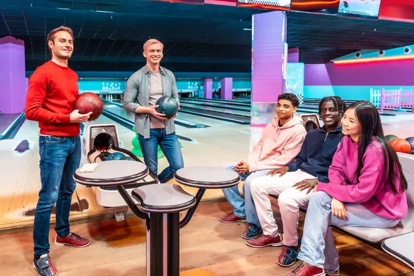 Çok ırklı bir arkadaş grubu sokakta eğlenceli bir bowling oyunu oynuyor, kahkahaları paylaşıyor ve birlikte neşeli anılar yaratıyorlar.