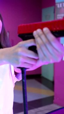 Genç bir kadın oyun salonunda atış oyunu oynayarak eğleniyor. Oyuncak tabancayla nişan alıp ateş ediyor.