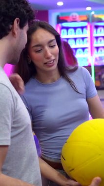 Romantik çift, neşeli bowling buluşmasının tadını çıkarırken, samimi bir öpüşmeyi paylaşıyor, gülüyor ve renkli bir ara sokakta kaynaşıyor.