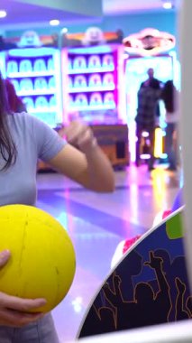 Mutlu çift bovling salonunda eğleniyor, bowling topu tutarken şakalaşıyorlar.