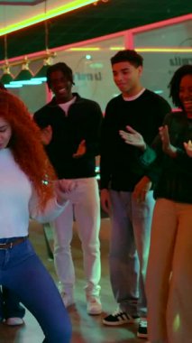 Enerjik arkadaşlar gece hayatından zevk alıyorlar, ritmik hareket ediyorlar ve hareketli bir kulüp atmosferinde dans ederek neşeyi ifade ediyorlar.