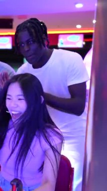 Canlı bowling salonunda heyecan verici bir motosiklet yarışı sırasında yarışan ve tezahürat yapan bir grup arkadaş, keyifli vakit ve beraberlik anlarını paylaşıyorlar.