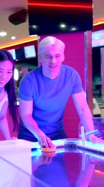 Genç yetişkinler hava hokeyi, gösterişli dostluk ve canlı bir atari salonunda rekabetin tadını çıkarıyorlar.