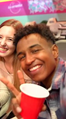 Bir grup genç yetişkin enerjik bowling gecesinin tadını çıkarıyor, kahkahaları, içkileri paylaşıyor, canlı eğlence ortamında unutulmaz sosyal anlar yaratıyorlar.