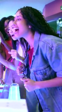 Genç insanlar hokey oynayarak eğleniyor, neşeli bir oyun salonunda gülüp tezahürat yapıyorlar.