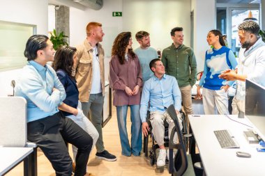 Modern bir ofiste, proje yöneticilerini dinleyen yaratıcı profesyoneller.