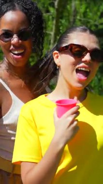 Çok kültürlü arkadaşlar güneşli bahçe partisinde neşeli bir şekilde kaynaşırlar, içeceklerin tadını çıkarırlar ve neşeli anları paylaşırlar parlak gülümsemeler ve pozitif enerjiyle.