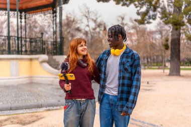 Sosyal medya için bir video kaydederken iki genç içerik yaratıcısı parkta yürüyor