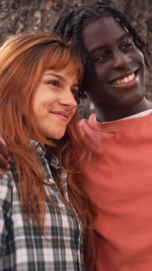 Çeşitli genç çiftler neşeli selfie çekiyorlar, güneşli park manzarasında birlikte yürürken neşeli anları yakalıyorlar, gerçek mutluluğu ve bağlantıyı paylaşıyorlar.