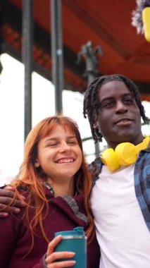 Genç içerik yaratıcıları açık havada bir video blogu kaydediyor. Mikrofonu ve teli olan bir akıllı telefon kullanıyorlar.