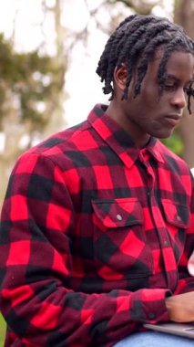 İki üniversite öğrencisi parkta dizüstü bilgisayar kullanarak bir projede işbirliği yapıyor, takım çalışması ve odaklanmış öğrenme gösterileri yapıyor.