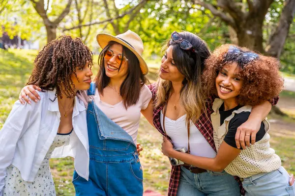 Dört farklı genç kadın parkta güneşli bir günün tadını çıkarıyorlar. Birbirlerine sarılıyorlar ve gülümsüyorlar. Arkadaşlıklarını kutluyorlar.