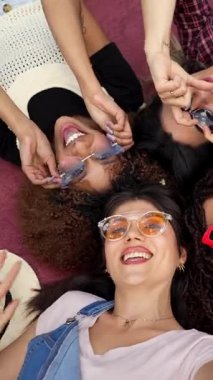 Kırmızı battaniyeyle bağlanan, şık güneş gözlüğü takan ve birlikte eğlenceli anlar yaratan genç kadınlar neşe ve kaygısız arkadaşlıkları ifade ederler.